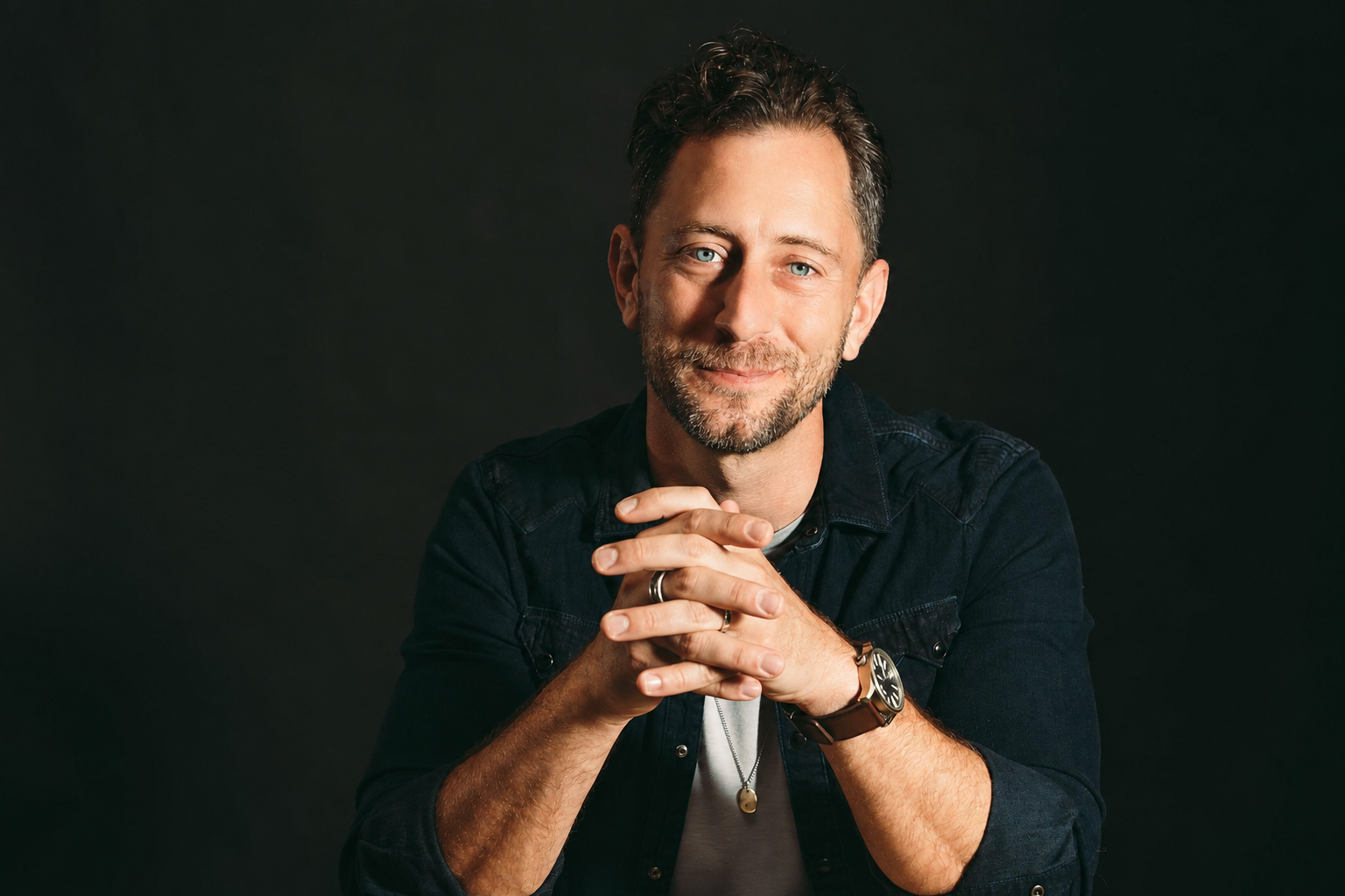 Portrait of Jeremy Falk with hands clasped